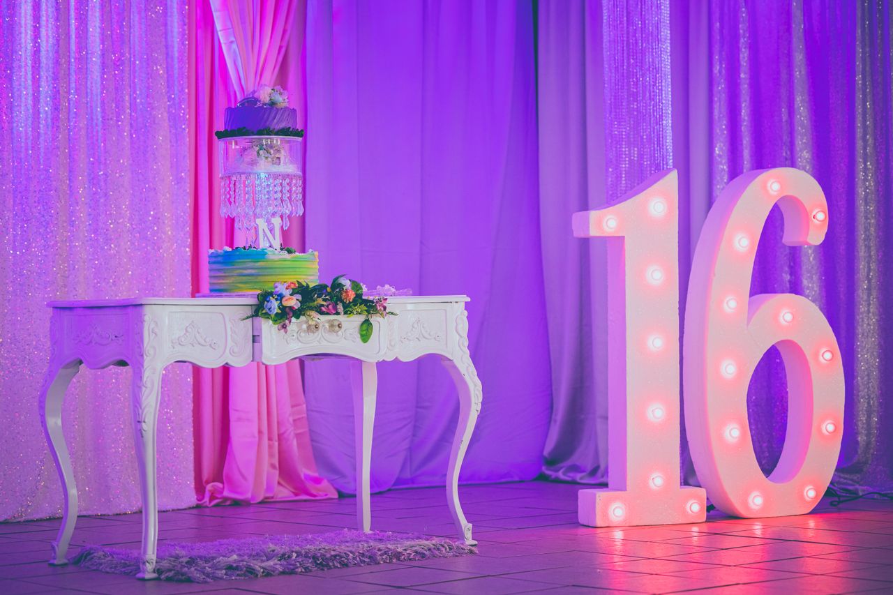 Vibrant sweet sixteen party decor with an elegant cake and illuminated number 16.